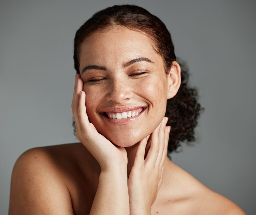 Woman smiling against dark grey background.